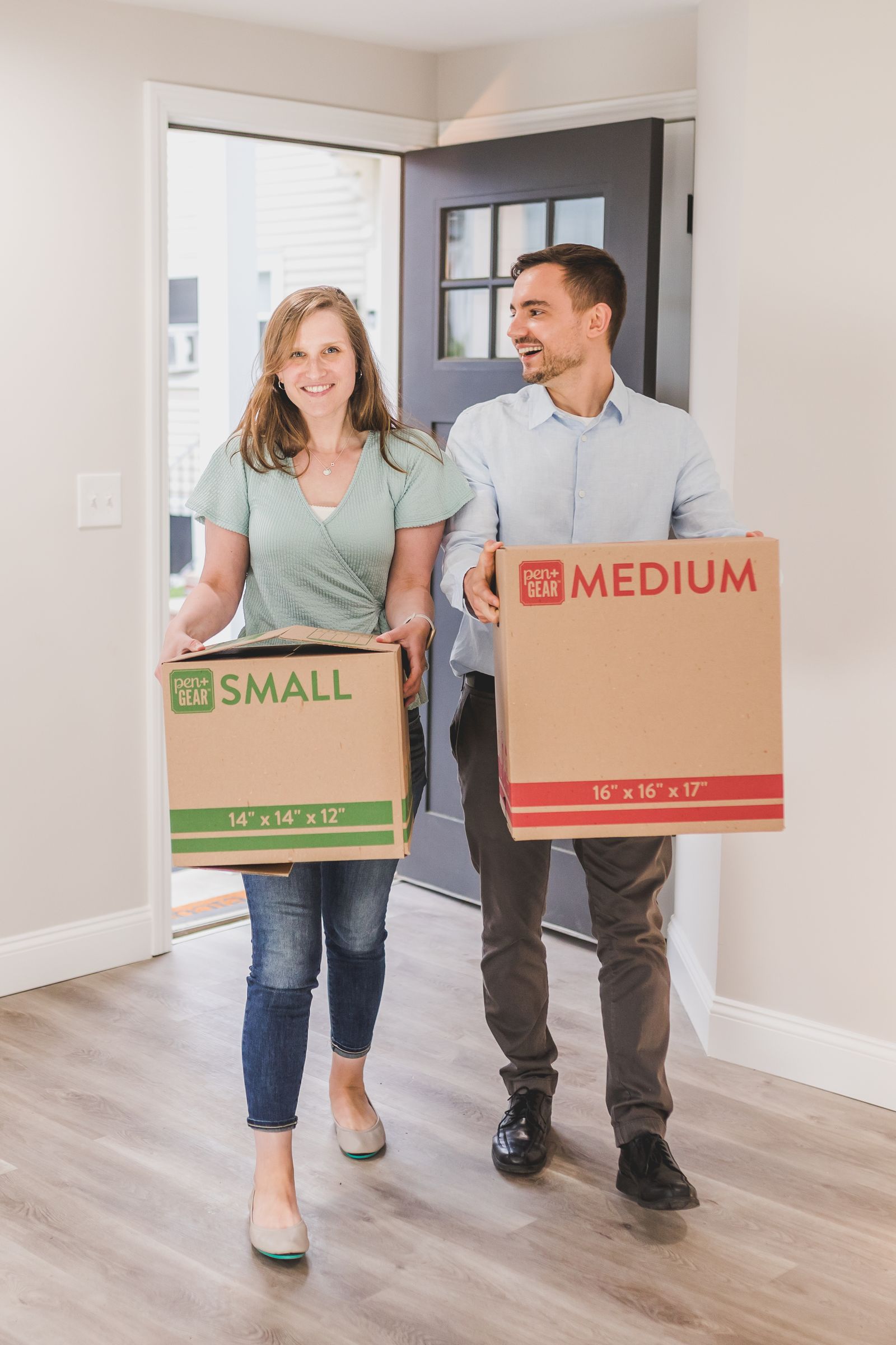 Couple carrying moving boxes into a home